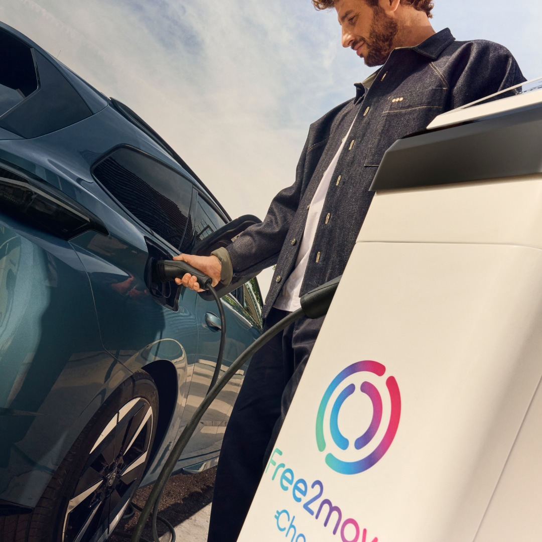 Hombre cargando un PEUGEOT E-308 SW en un punto de recarga Free2move Charge