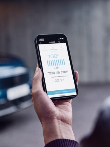 Mujer con smartphone delante del PEUGEOT E-3008 Dual Motor